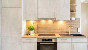 Una cocina moderna con armarios de madera clara, lavavajillas de acero inoxidable y horno empotrado.
