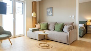 Una sala de estar con un sofá, una mesa redonda, una silla y un televisor.