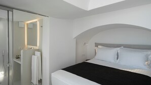 Ein modernes Schlafzimmer mit Bett, begehbarem Kleiderschrank und einem Badezimmer mit Dusche.