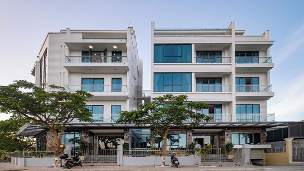 Un immeuble à plusieurs étages doté de balcons, de grandes fenêtres et d’un espace d’entrée abrité.