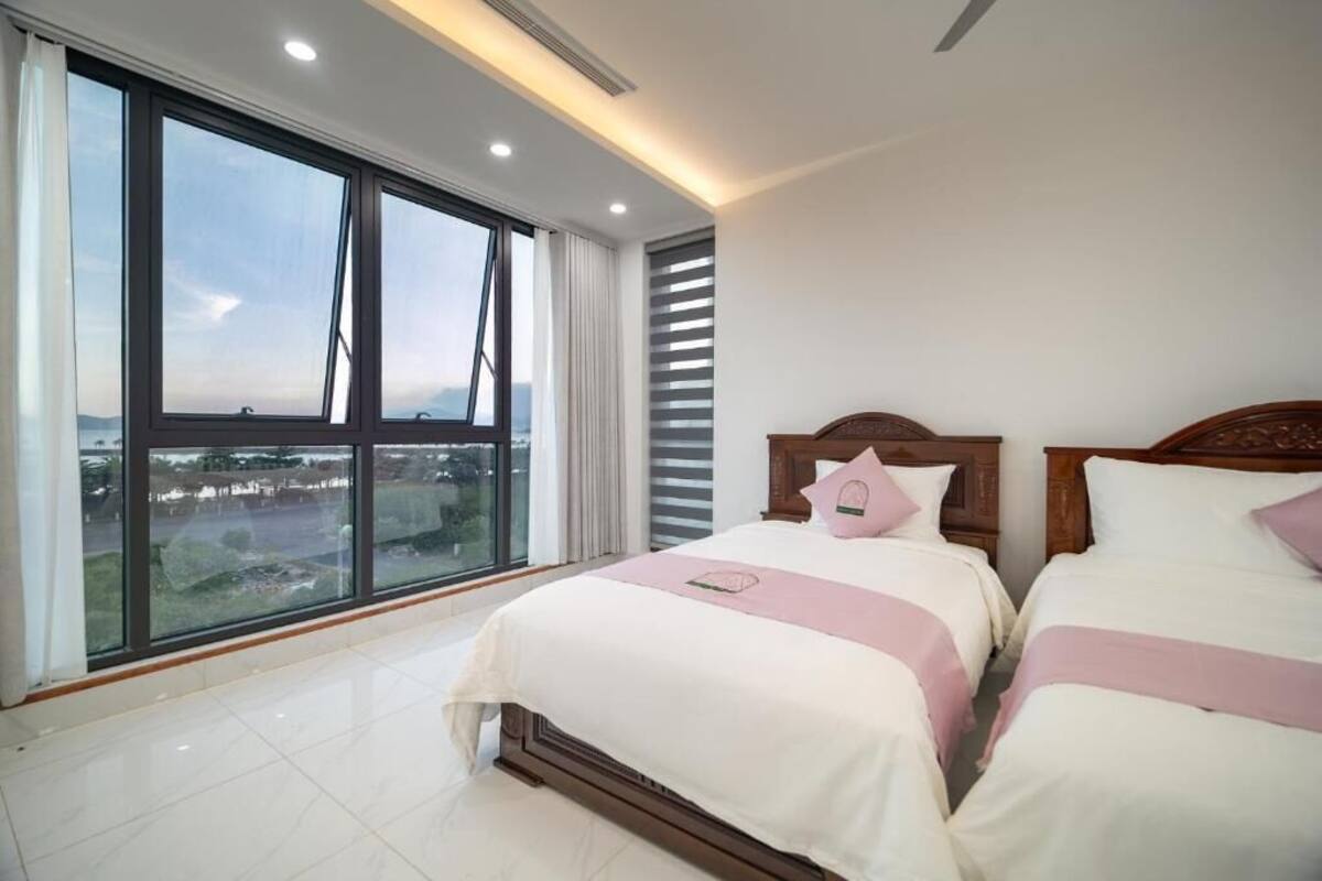 Ein Schlafzimmer mit zwei Betten, großen Fenstern und Blick auf die Stadt.