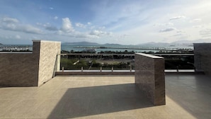 Une terrasse offrant une vue sur un plan d’eau, un pont et des montagnes lointaines.
