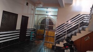 A staircase with a handrail, a chandelier, and a metal gate with a window.