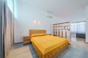 Un dormitorio moderno con una cama de madera, mesitas de noche, un armario empotrado y un gran ventanal con cortinas.