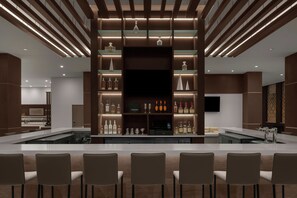 A modern bar area with a long counter, multiple seating options, and a variety of bottles and glasses on display. - AC Hotels by Marriott Sacramento Folsom (Folsom)