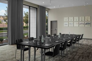 Un salón de conferencias con una larga mesa, sillas y una botella de agua sobre la mesa.