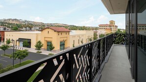 A balcony with a view of a cityscape, including buildings and a hilly background.