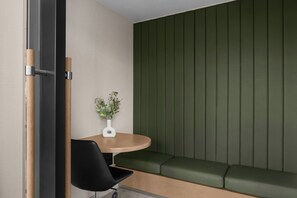 A modern room with a green padded bench, a round wooden table with a white vase, and a black chair. - AC Hotels by Marriott Sacramento Folsom (Folsom)