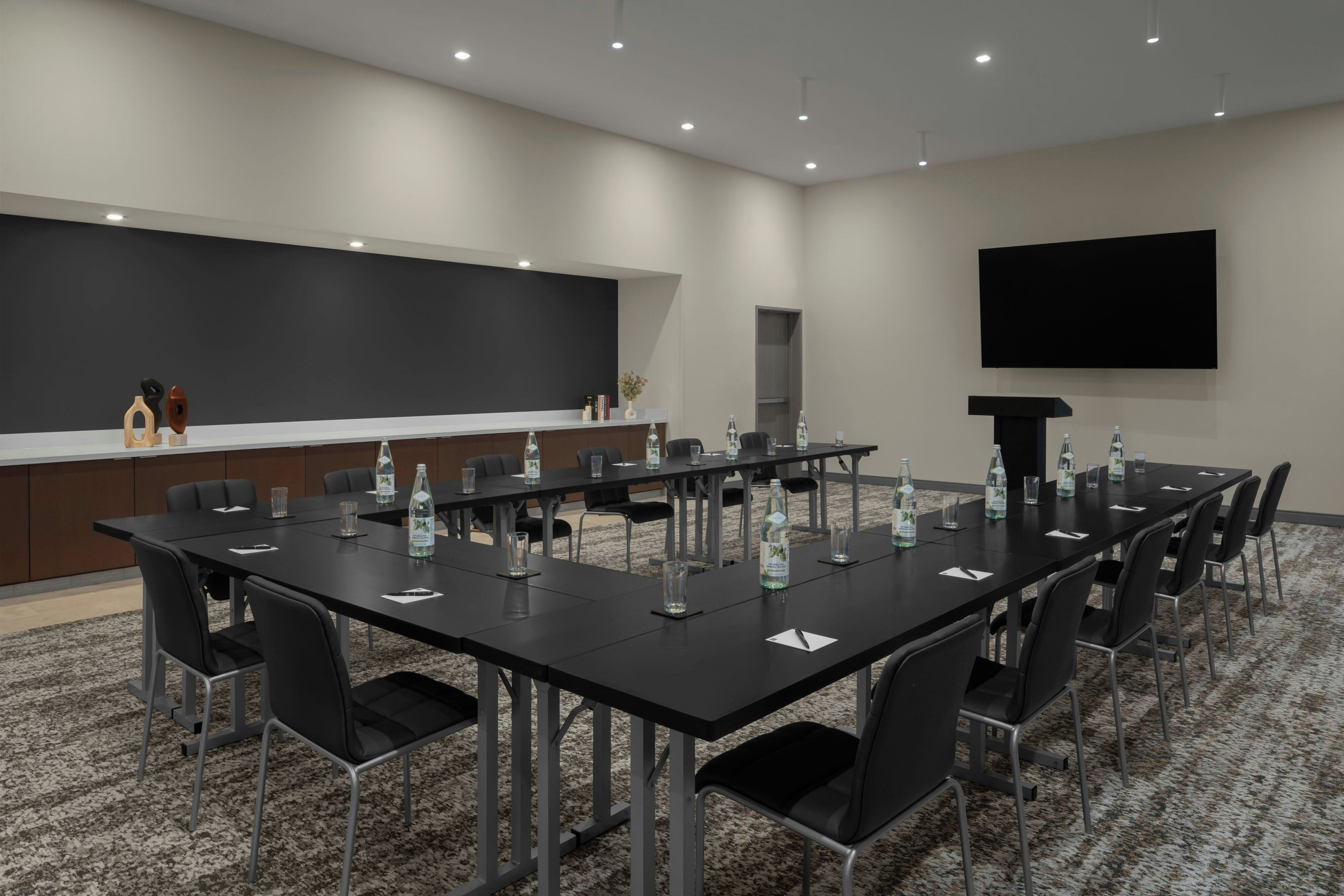 Un salón de conferencias con una larga mesa, sillas y un televisor de pantalla plana en la pared.