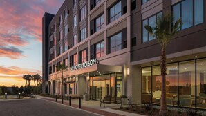 A modern hotel building with a flat facade, large windows, and a sign reading 'AC HOTEL FOLSOM'.