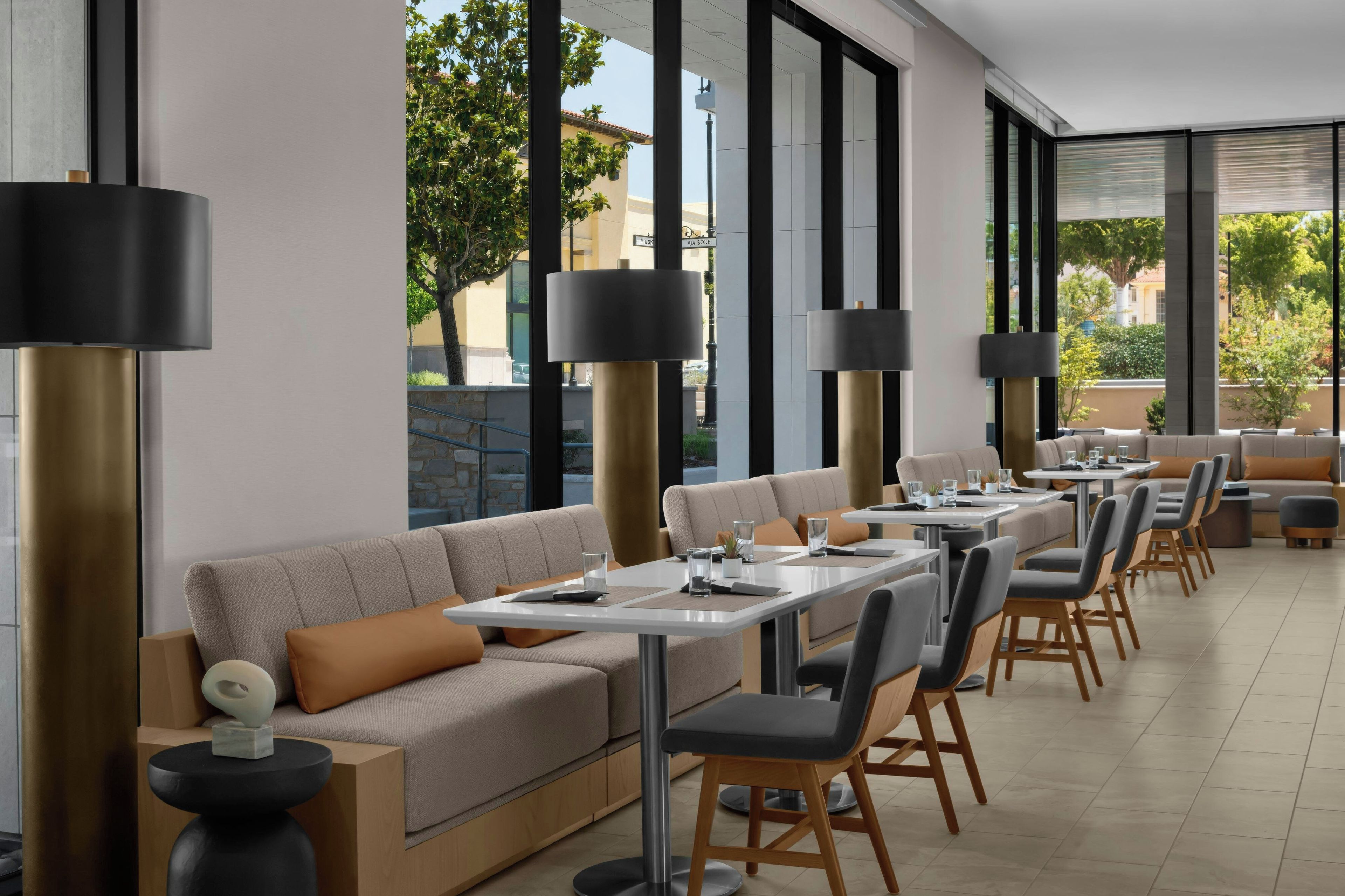 A modern restaurant with a long counter, cushioned seating, and large windows.