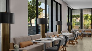 A modern restaurant with a long counter, cushioned seating, and large windows.