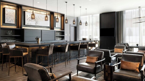 A modern bar area with leather chairs, pendant lighting, and a large flat-screen TV. - AC Hotels by Marriott Sacramento Folsom (Folsom)