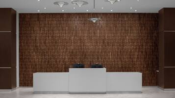 A reception area with a wooden panel wall, a white reception desk, and pendant lighting.