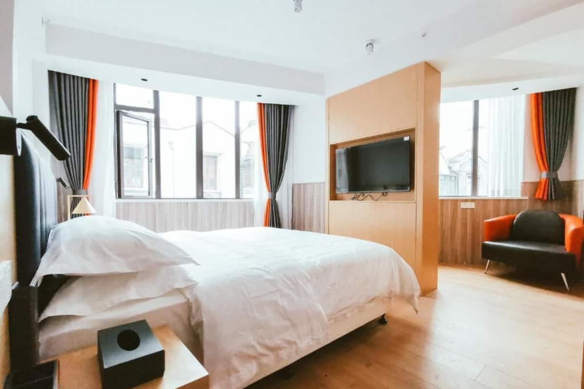 Een hotelkamer met een bed, een aan de muur bevestigde televisie, een bureau met een lamp en een stoel.