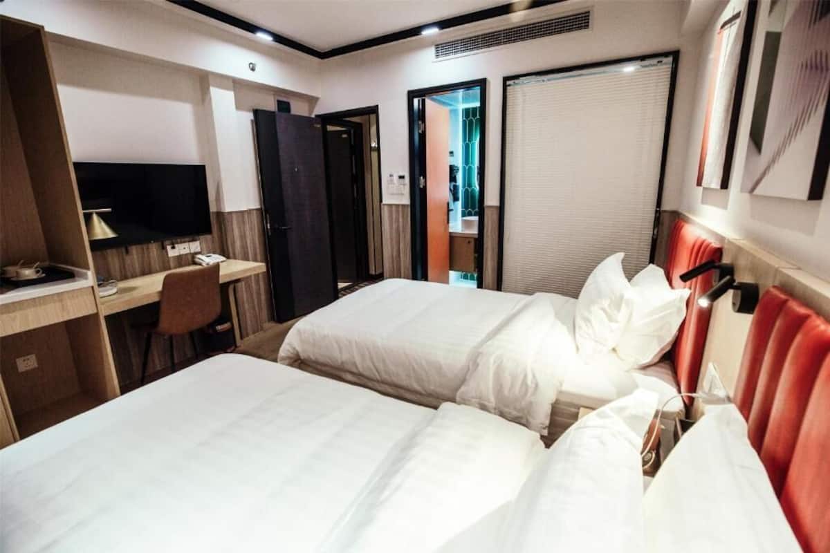 Een hotelkamer met twee bedden, een bureau met stoel, een televisie en een kledingkast.