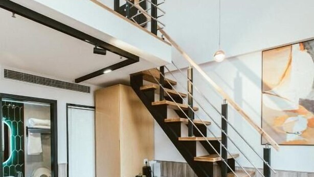 Ein modernes Interieur mit einem braunen Ledersofa, einer Treppe und einem großen abstrakten Gemälde.