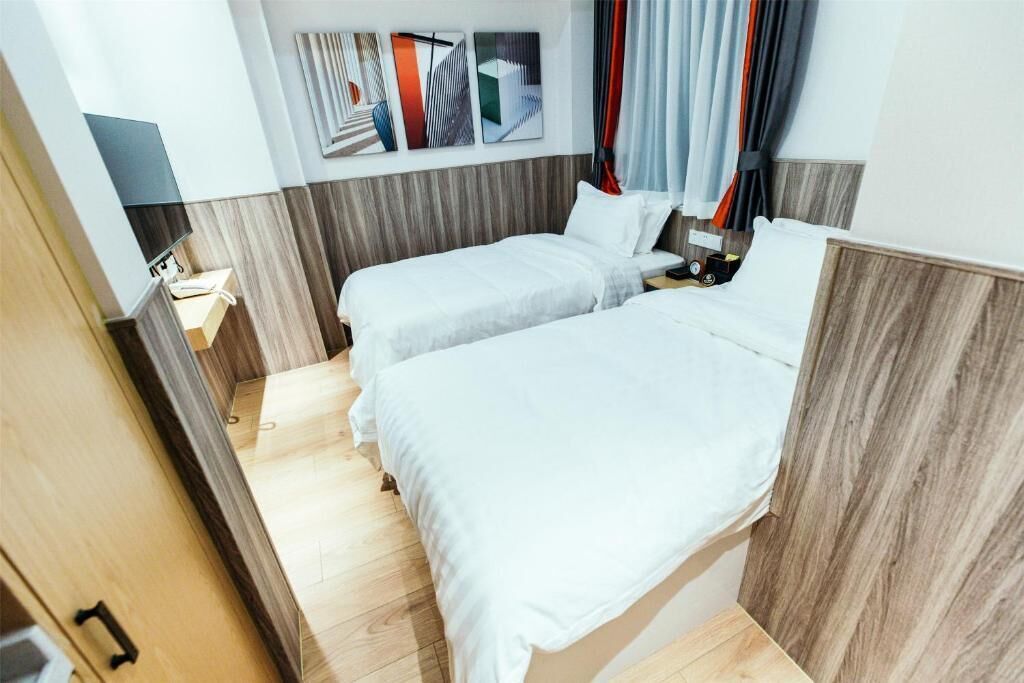 Habitación de hotel con dos camas, un televisor, una mesita de noche y una obra de arte colgada en la pared.
