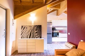 A modern kitchen with white cabinets, a zebra print artwork, and a wooden ceiling.