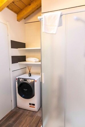 Zona de bugaderia amb una rentadora, un escuraprius i una tovallola penjant d'una porta.