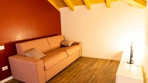 Ein Zimmer mit Holzboden, einer Couch, einem weißen Beistelltisch und einer roten Wand.