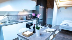 Eine moderne Küche mit Einbauofen, Kühlschrank und einem Essbereich mit Tisch für zwei Personen.