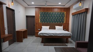 Een moderne hotelkamer met een groot bed, een houten hoofdbord, een bureau en een zithoek.