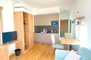 Un espacio habitable compacto con kitchenette, comedor y zona de estar.