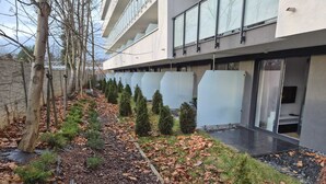 A modern building with a glass facade, a pathway lined with trees and shrubs, and a stone wall on one side. - Modern studio near Krakow Old Town + WiFi (Kraków)