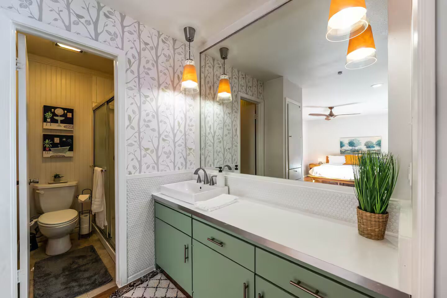A bathroom with a toilet, sink, and cabinet, a mirror, and a ceiling fan.