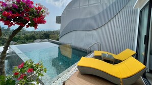 Una piscina infinita moderna con agua cristalina, rodeada por una terraza de madera y sillas de descanso amarillas.