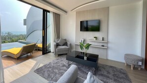 Una sala de estar moderna con un televisor grande, un sofá, una mesita de centro y vista al océano.
