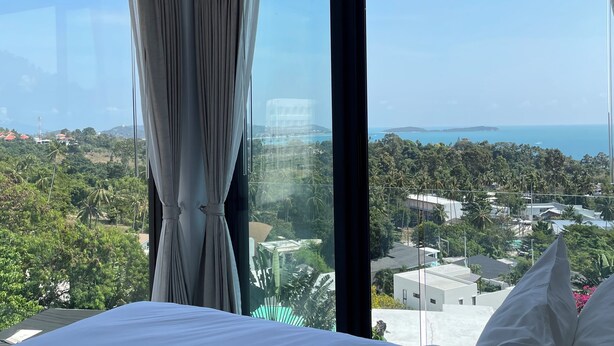 Habitación de hotel con una cama grande, vistas a la ciudad y un balcón.