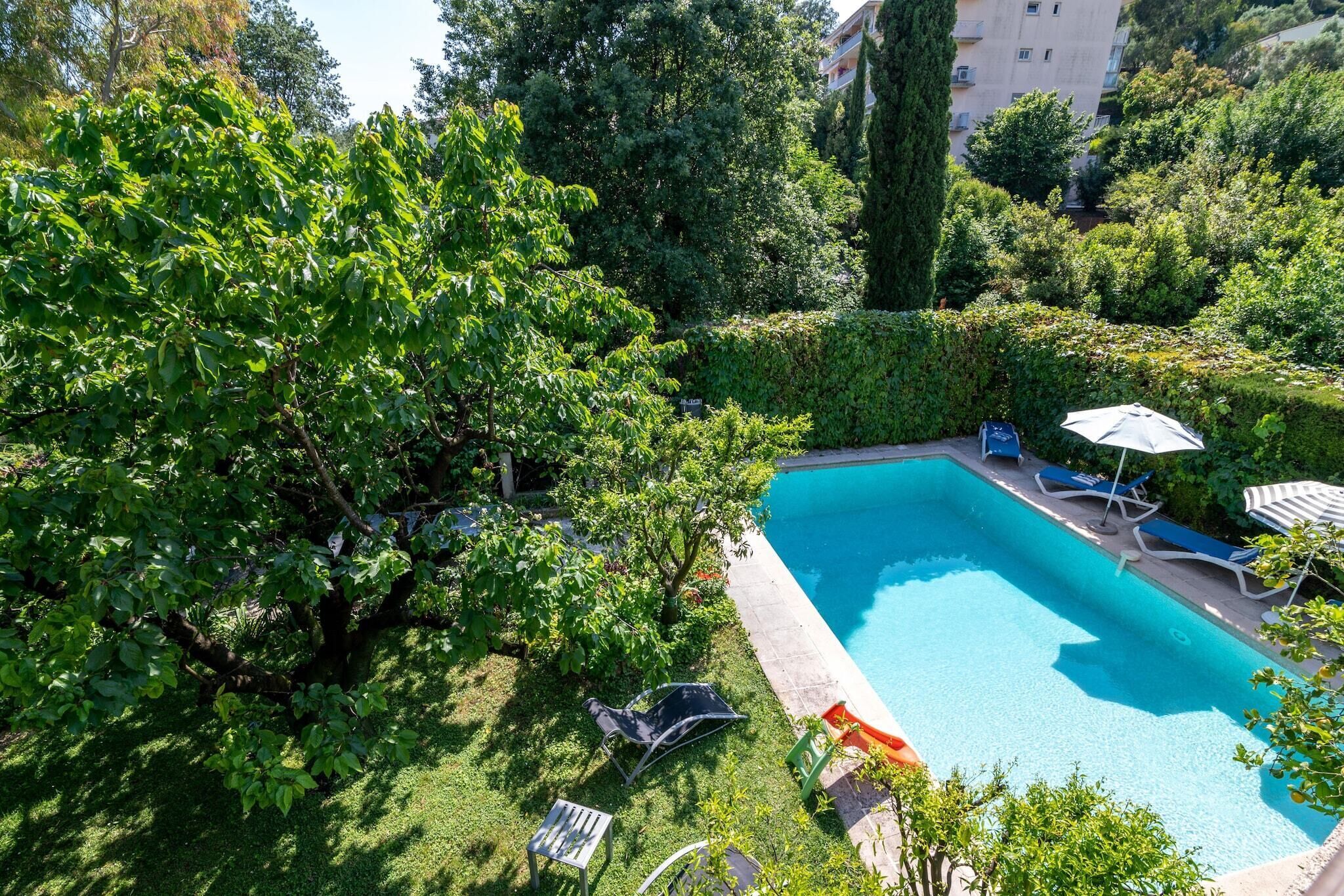 Una piscina circondata da vegetazione lussureggiante, con lettini e ombrelloni.