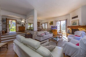 Un salon spacieux doté d’une cheminée, d’un ensemble de canapés, d’un téléviseur et offrant une vue sur l’extérieur.