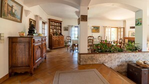 A spacious living area with a dining table, chairs, a wooden cabinet, and a stone wall. - Provencial Villa in Vence with Private Swimming Pool (Vence)