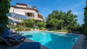 A swimming pool with lounge chairs, a covered umbrella, and a building with a balcony. - Provencial Villa in Vence with Private Swimming Pool (Vence)