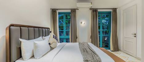 A bedroom with a bed, curtains, a ceiling fan, and an air conditioning unit.