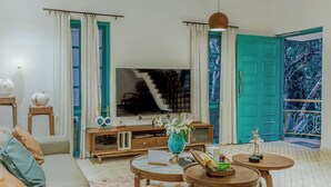 Una sala de estar con televisión, sofá, mesa de centro y una puerta color aguamarina.