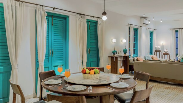 Comedor con una mesa redonda, sillas, una cesta de fruta y bebidas de naranja.