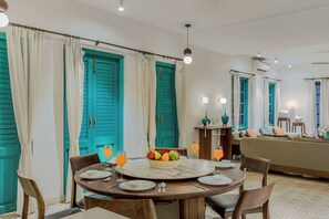 A dining area with a round table, chairs, a fruit basket, and orange drinks. - ELIVAAS Casa Lotus 3 BHK Villa with Pool (Siolim)