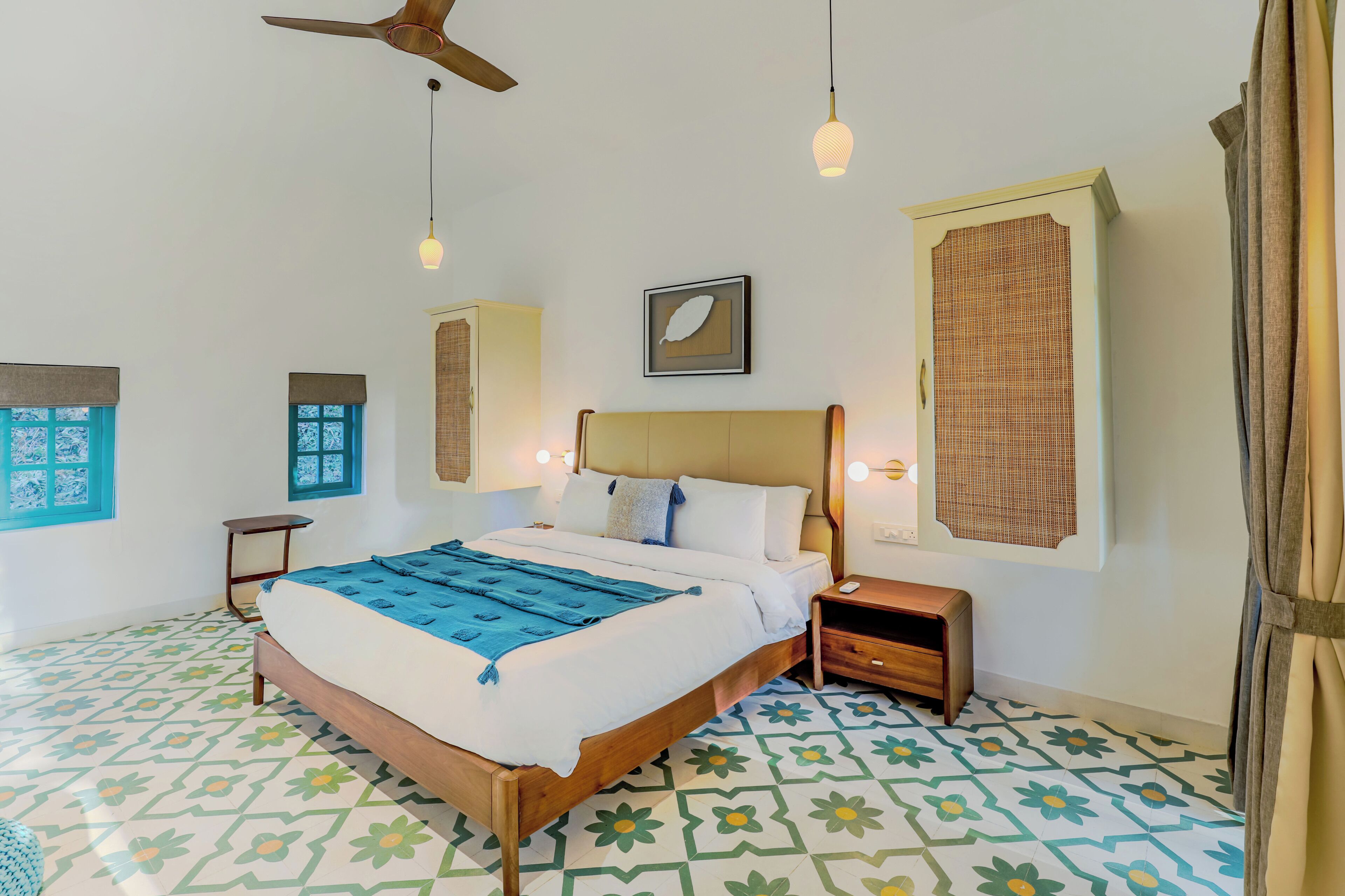 A bedroom with a bed, bedside tables, a ceiling fan, and a patterned floor.