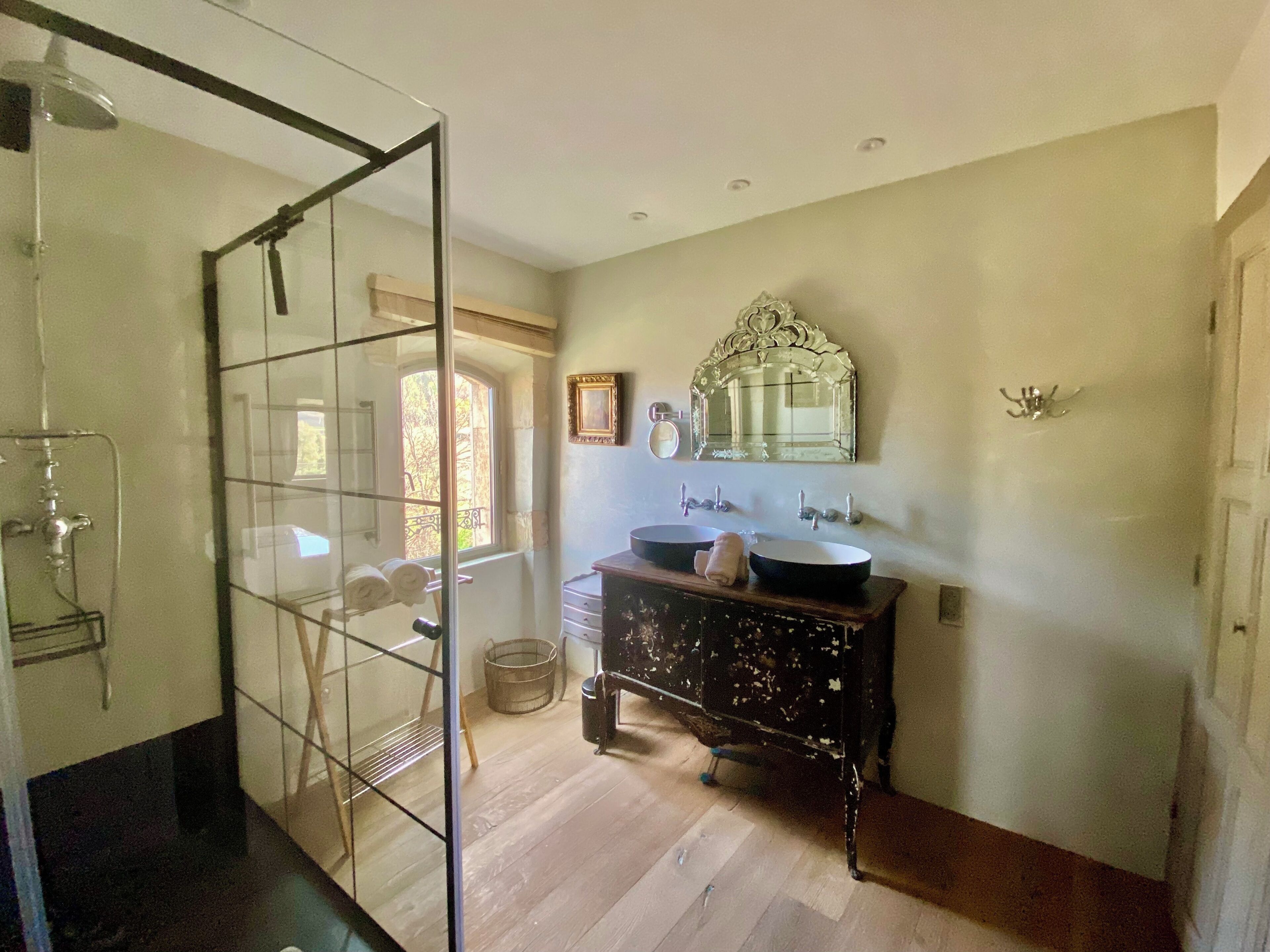 A bathroom with a glass shower enclosure, a wooden vanity with two sinks, and a large mirror above the vanity.