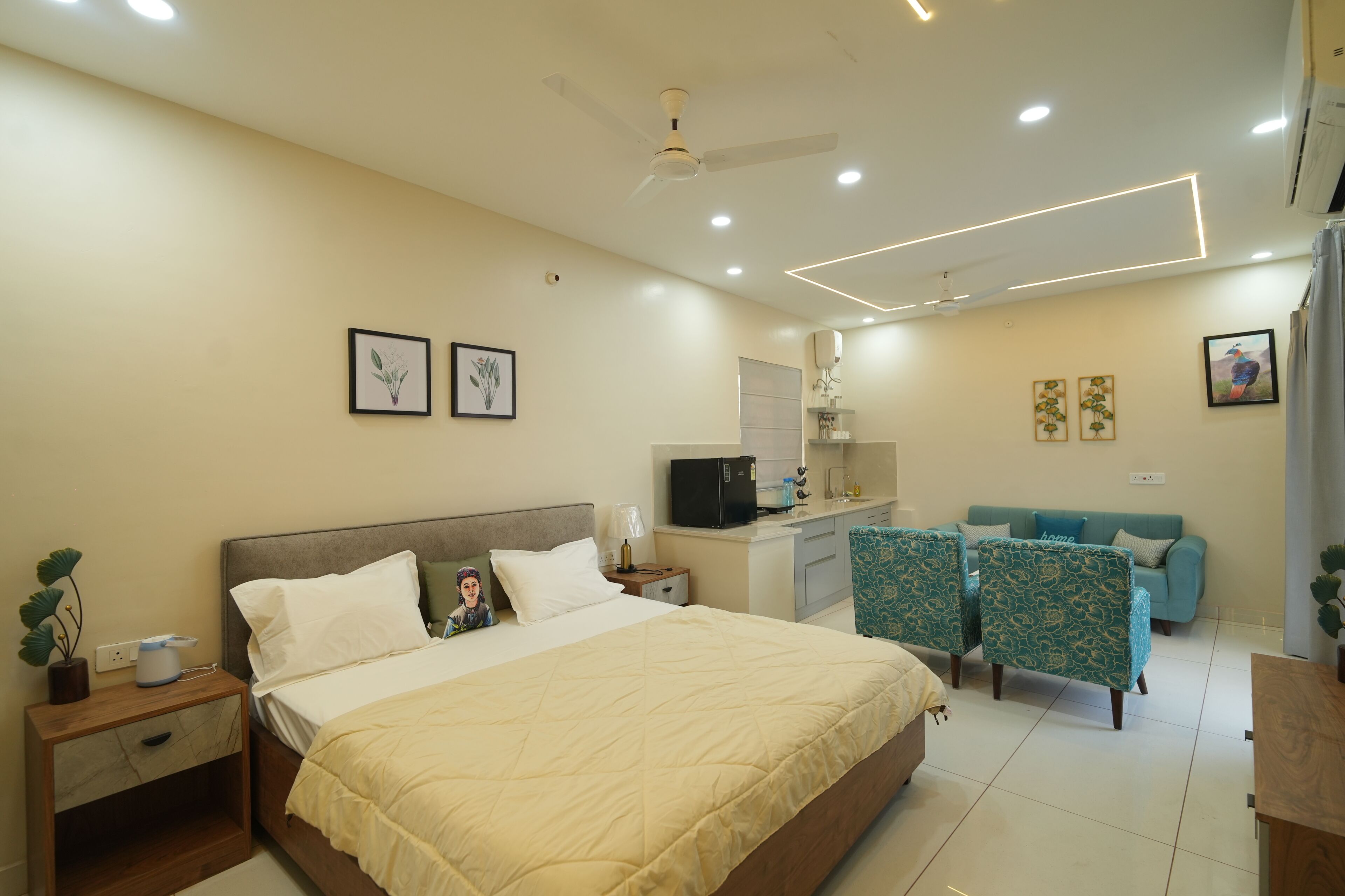 A bedroom with a bed, nightstands, a desk, a sofa, and two patterned chairs.