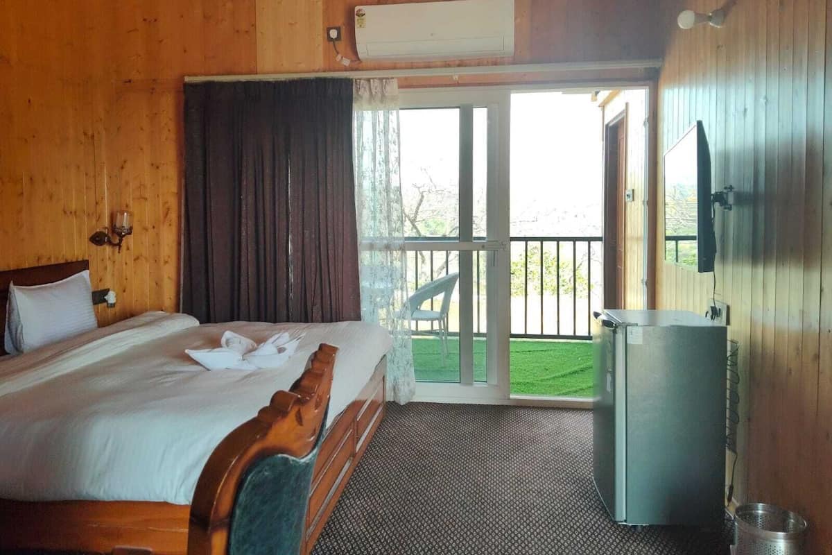 A wooden room with a bed, a window, and a balcony.