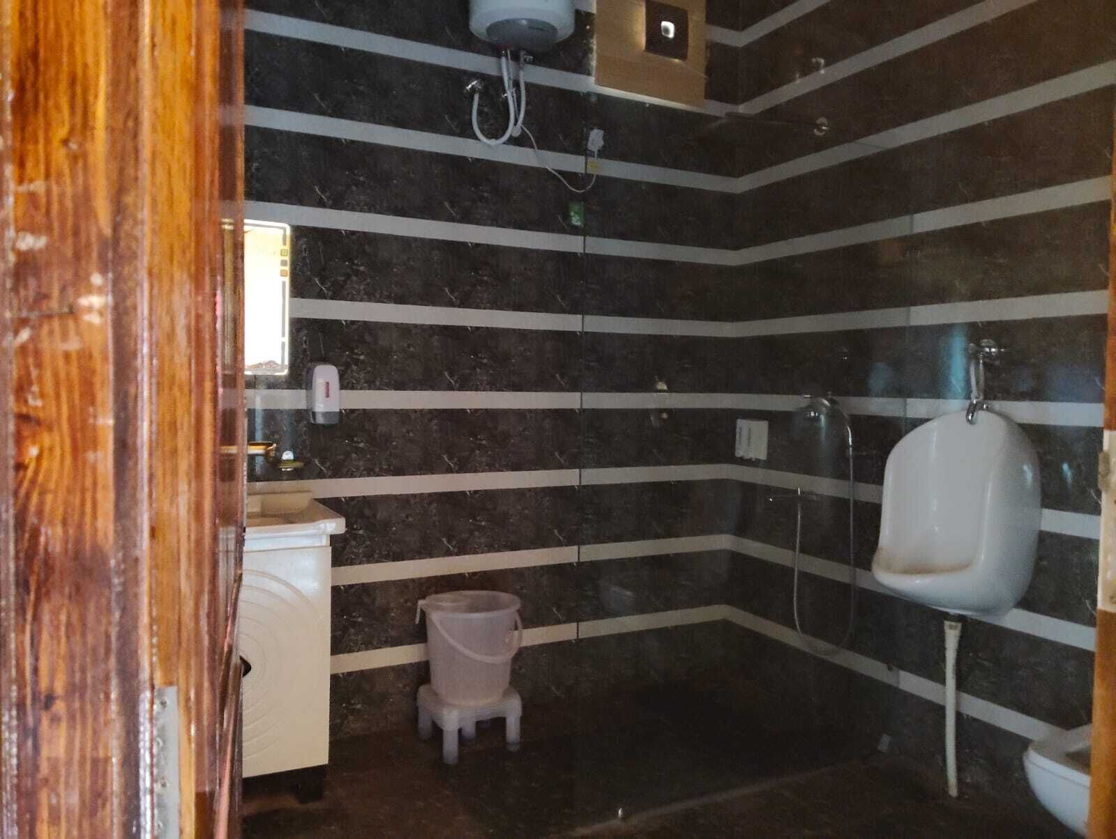 Un baño con paredes de mármol a rayas, un lavabo blanco, un pequeño cubo de basura y un orinal.
