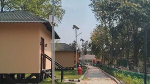 A pathway lined with solar-powered street lamps, a grassy area, and buildings with a uniform architectural style. - Thorn Kitchen &Hideaways (Hoshiarpur)