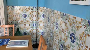 Een kamer met blauwe wanden, een betegelde spatwand met een patroon, een houten eettafel en een vloerlamp.