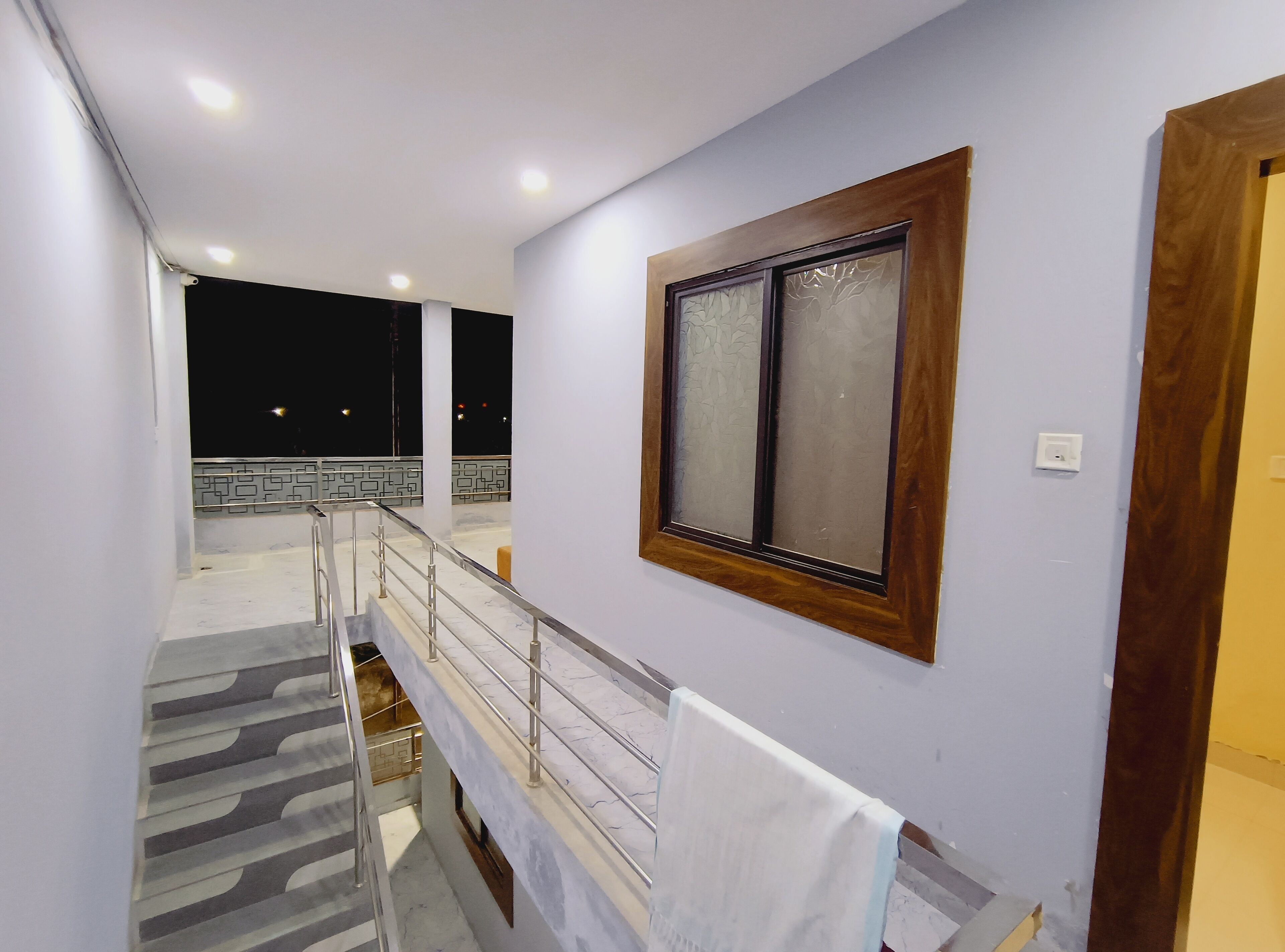 Ein Hotelgang mit Treppe, einem Holzrahmenfenster und einer weißen Wand.