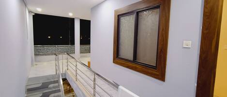 Ein Hotelgang mit Treppe, einem Holzrahmenfenster und einer weißen Wand.